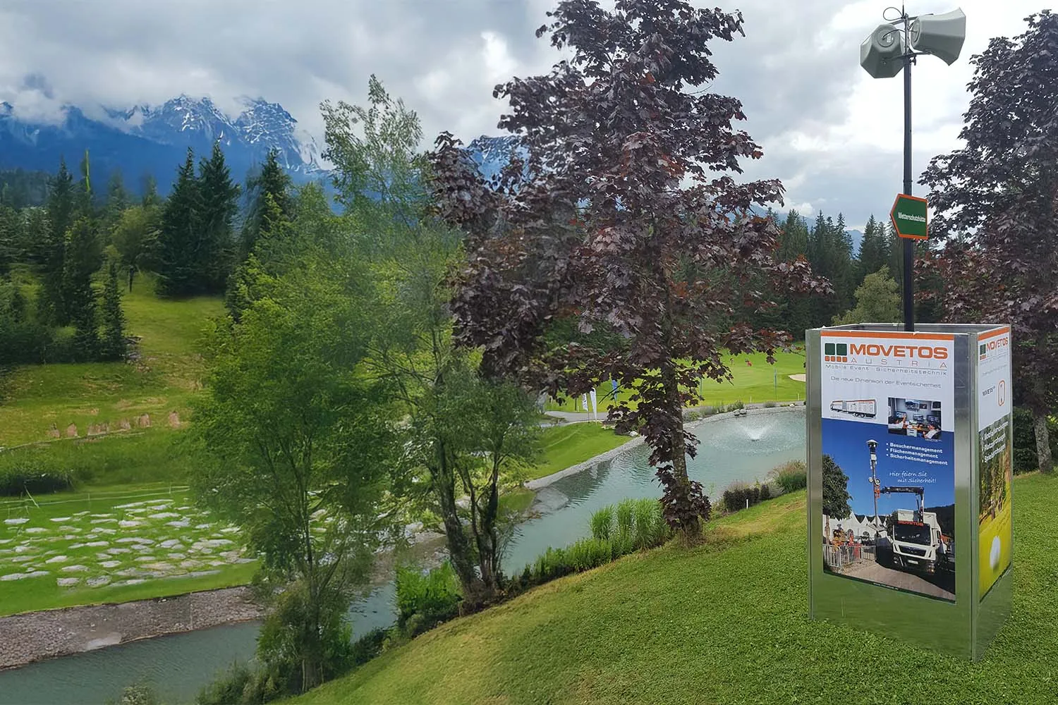 Besucher-Durchsage-System mit Lautsprecher und MOVETOS-Beschriftung auf einer Grünfläche vor Bergkulisse