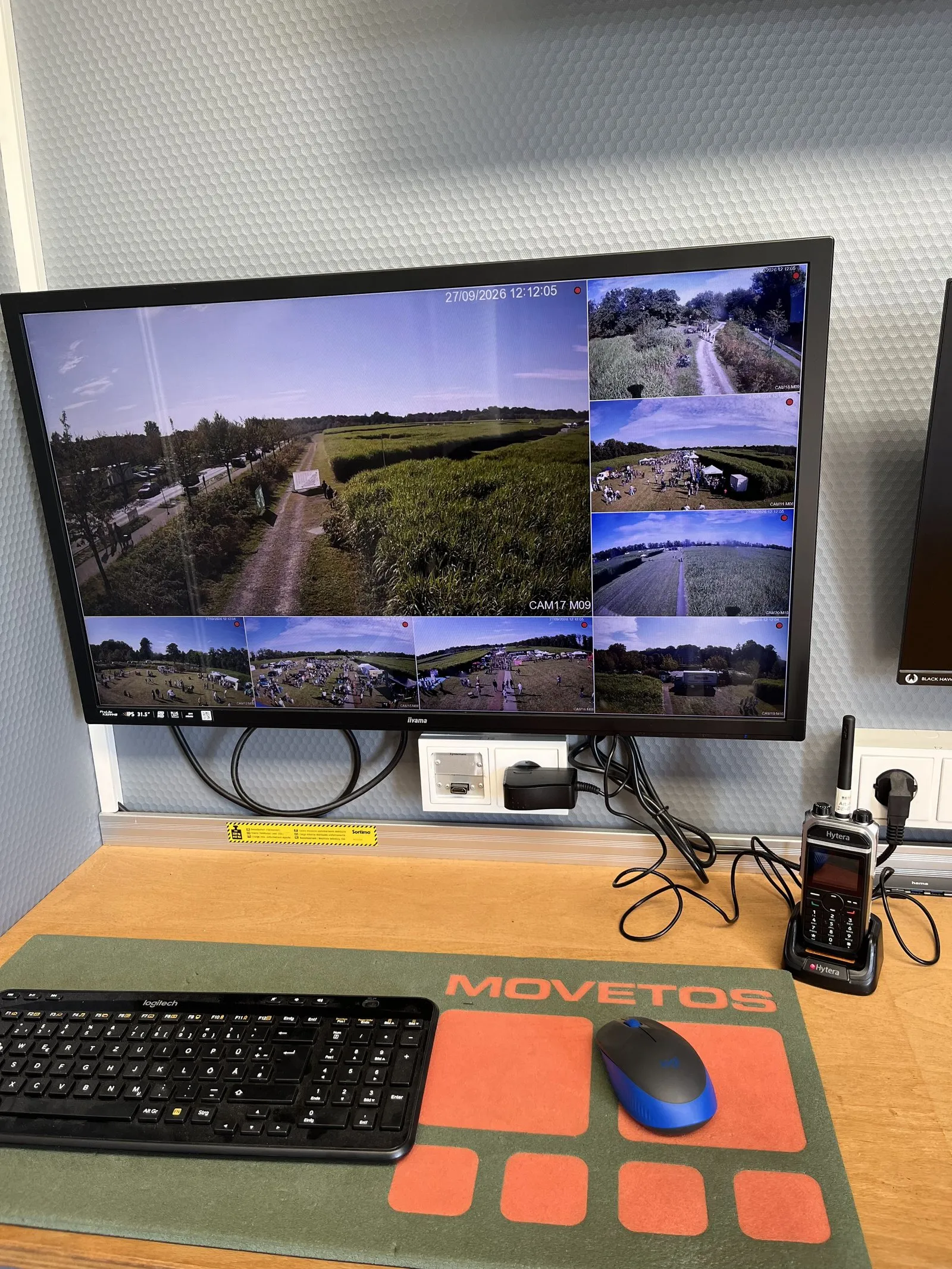 Monitor in der mobilen Leitstelle mit mehreren Kamerabildern vom Gelände, daneben ein Funkgerät