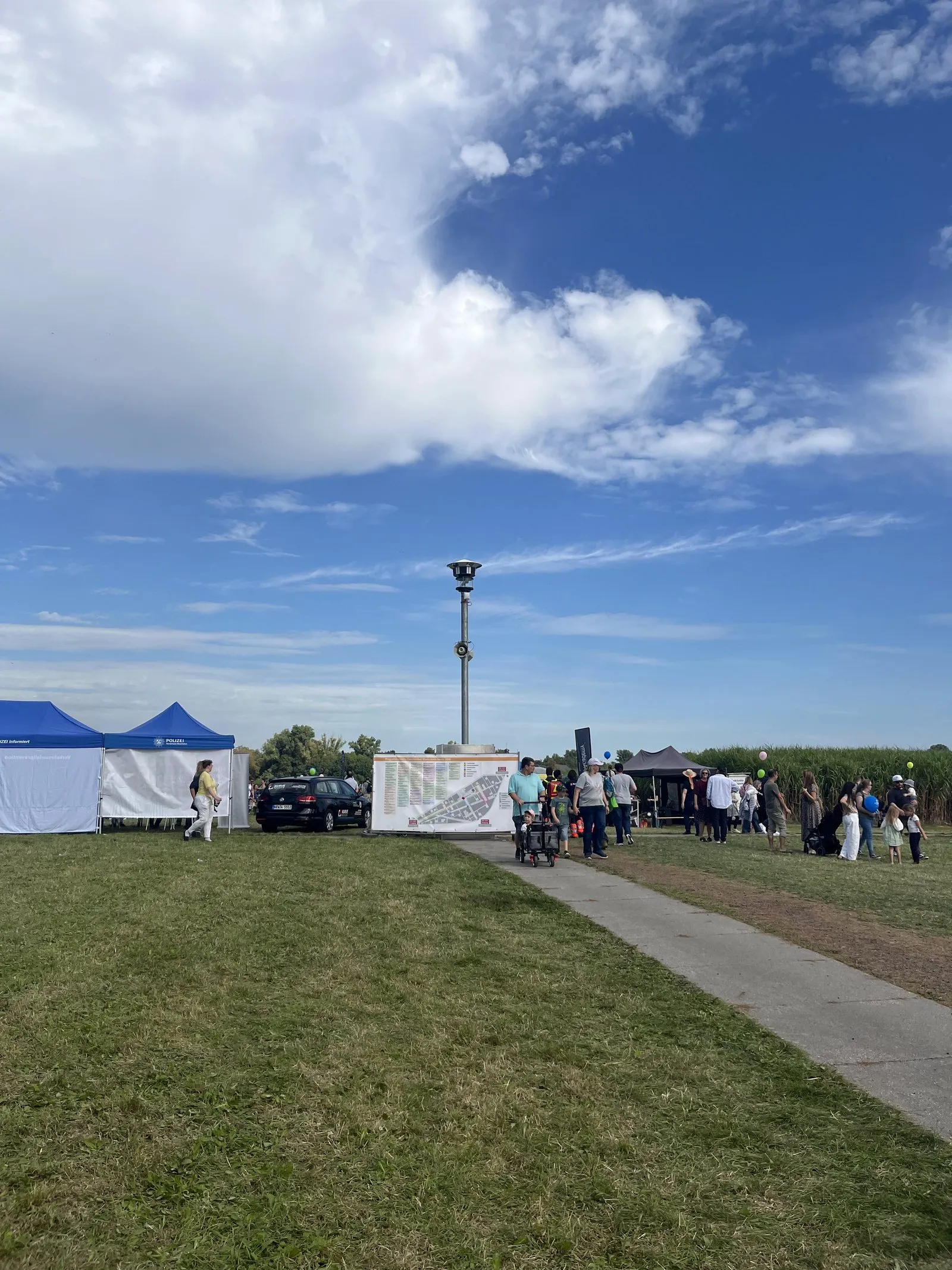 Mast mit Kamera auf der Festwiese in Neuss, im Hintergrund Zelte und Besucher