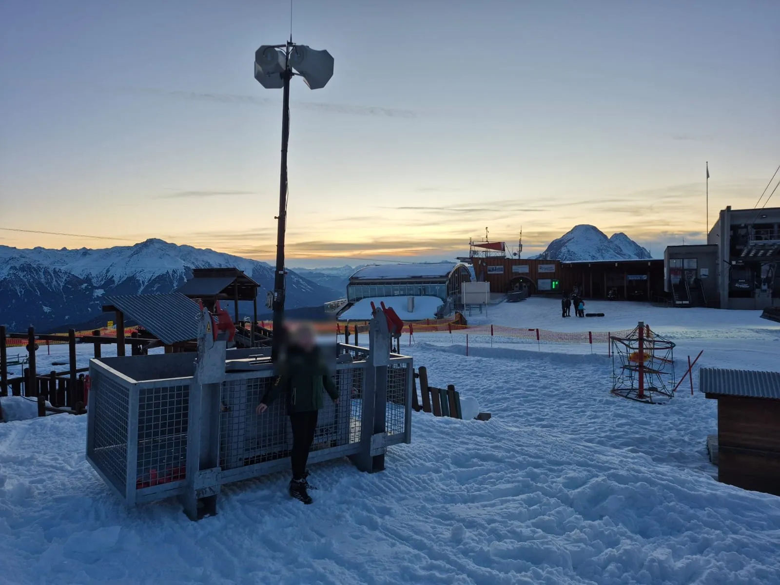 Lautsprechermast an der Bergstation in der Abenddämmerung, dahinter die Tiroler Berge